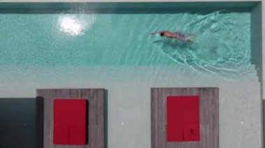 Bir adam havuzunda dinleniyor, lüks bir yüzme havuzunda tek başına yüzüyor, yüzücü adam lüks bir villada havuza dalıyor. Havadan çekim. Dikkatsiz yaz tatili imajı. tatil 
