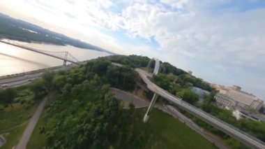 KIEV, Ukrayna - 19 Nisan 2021: FPV drone, Reunion Arch, Kyiv: Halkların Dostluk Kemeri ve Volodymyr Tepesi köprüsü. Kiev 'deki parkın ve yaya köprüsünün manzarası. Parktaki insanlar ve yeşil ağaçlar. 