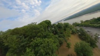 KIEV, Ukrayna - 19 Nisan 2021: FPV drone, Reunion Arch, Kyiv: Halkların Dostluk Kemeri ve Volodymyr Tepesi köprüsü. Kiev 'deki parkın ve yaya köprüsünün manzarası. Parktaki insanlar ve yeşil ağaçlar. 