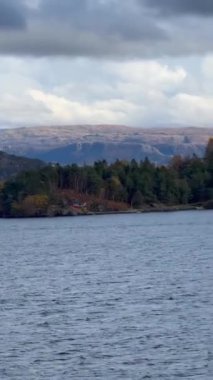 Norveç 'te gezinti. Bottan fiyordun manzarası, tekneden dağların manzarası, şelaleler, yolcu gemileri ve hassas tekneler turistleri gemiden kıyıya taşıyan mavi gökyüzü ile güzel bir günde