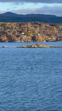 Norveç 'te gezinti. Bottan fiyordun manzarası, tekneden dağların manzarası, şelaleler, yolcu gemileri ve hassas tekneler turistleri gemiden kıyıya taşıyan mavi gökyüzü ile güzel bir günde