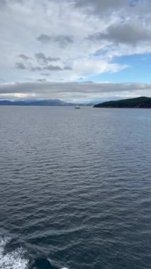 Norveç 'te gezinti. Bottan fiyordun manzarası, tekneden dağların manzarası, şelaleler, yolcu gemileri ve hassas tekneler turistleri gemiden kıyıya taşıyan mavi gökyüzü ile güzel bir günde