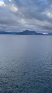 Norveç 'te gezinti. Bottan fiyordun manzarası, tekneden dağların manzarası, şelaleler, yolcu gemileri ve hassas tekneler turistleri gemiden kıyıya taşıyan mavi gökyüzü ile güzel bir günde