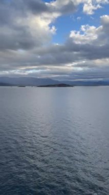 Norveç 'te gezinti. Bottan fiyordun manzarası, tekneden dağların manzarası, şelaleler, yolcu gemileri ve hassas tekneler turistleri gemiden kıyıya taşıyan mavi gökyüzü ile güzel bir günde