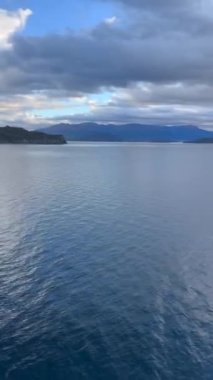 Norveç 'te gezinti. Bottan fiyordun manzarası, tekneden dağların manzarası, şelaleler, yolcu gemileri ve hassas tekneler turistleri gemiden kıyıya taşıyan mavi gökyüzü ile güzel bir günde