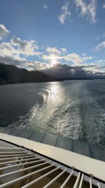 Norveç 'te gezinti. Bottan fiyordun manzarası, tekneden dağların manzarası, şelaleler, yolcu gemileri ve hassas tekneler turistleri gemiden kıyıya taşıyan mavi gökyüzü ile güzel bir günde