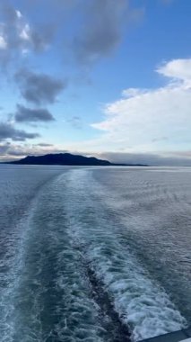 Norveç 'te gezinti. Bottan fiyordun manzarası, tekneden dağların manzarası, şelaleler, yolcu gemileri ve hassas tekneler turistleri gemiden kıyıya taşıyan mavi gökyüzü ile güzel bir günde