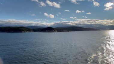 Norveç 'te gezinti. Bottan fiyordun manzarası, tekneden dağların manzarası, şelaleler, yolcu gemileri ve hassas tekneler turistleri gemiden kıyıya taşıyan mavi gökyüzü ile güzel bir günde