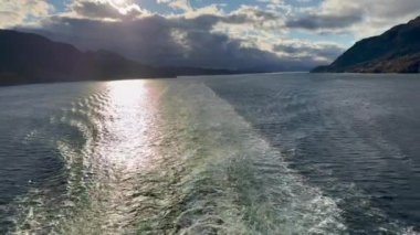 Norveç 'te gezinti. Bottan fiyordun manzarası, tekneden dağların manzarası, şelaleler, yolcu gemileri ve hassas tekneler turistleri gemiden kıyıya taşıyan mavi gökyüzü ile güzel bir günde