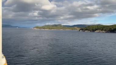 Norveç 'te gezinti. Bottan fiyordun manzarası, tekneden dağların manzarası, şelaleler, yolcu gemileri ve hassas tekneler turistleri gemiden kıyıya taşıyan mavi gökyüzü ile güzel bir günde