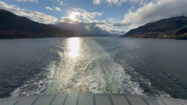 Norveç 'te gezinti. Bottan fiyordun manzarası, tekneden dağların manzarası, şelaleler, yolcu gemileri ve hassas tekneler turistleri gemiden kıyıya taşıyan mavi gökyüzü ile güzel bir günde