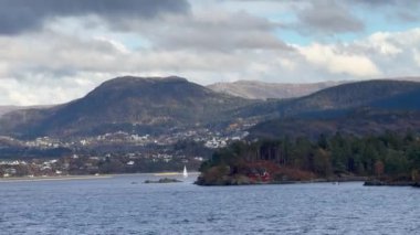 Norveç 'te gezinti. Bottan fiyordun manzarası, tekneden dağların manzarası, şelaleler, yolcu gemileri ve hassas tekneler turistleri gemiden kıyıya taşıyan mavi gökyüzü ile güzel bir günde