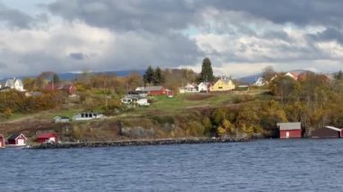 Norveç 'te gezinti. Bottan fiyordun manzarası, tekneden dağların manzarası, şelaleler, yolcu gemileri ve hassas tekneler turistleri gemiden kıyıya taşıyan mavi gökyüzü ile güzel bir günde