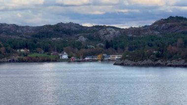 Norveç 'te gezinti. Bottan fiyordun manzarası, tekneden dağların manzarası, şelaleler, yolcu gemileri ve hassas tekneler turistleri gemiden kıyıya taşıyan mavi gökyüzü ile güzel bir günde