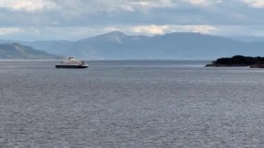 Norveç 'te gezinti. Bottan fiyordun manzarası, tekneden dağların manzarası, şelaleler, yolcu gemileri ve hassas tekneler turistleri gemiden kıyıya taşıyan mavi gökyüzü ile güzel bir günde