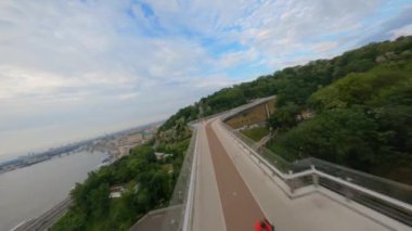 KIEV, Ukrayna - 19 Nisan 2021: FPV drone, Reunion Arch, Kyiv: Halkların Dostluk Kemeri ve Volodymyr Tepesi köprüsü. Kiev 'deki parkın ve yaya köprüsünün manzarası. Parktaki insanlar ve yeşil ağaçlar. 