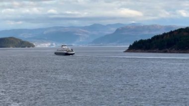 Norveç 'te gezinti. Bottan fiyordun manzarası, tekneden dağların manzarası, şelaleler, yolcu gemileri ve hassas tekneler turistleri gemiden kıyıya taşıyan mavi gökyüzü ile güzel bir günde