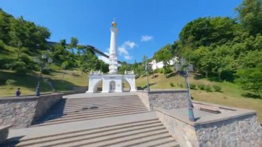 KIEV, Ukrayna - 19 Nisan 2021: FPV drone, Reunion Arch, Kyiv: Halkların Dostluk Kemeri ve Volodymyr Tepesi köprüsü. Kiev 'deki parkın ve yaya köprüsünün manzarası. Parktaki insanlar ve yeşil ağaçlar. 