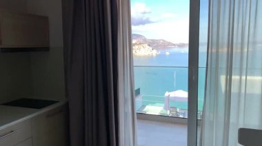 Açık bir pencereden deniz, kıyı şeridi ve Yunanistan 'ın mavi kepenkleri görünüyor.