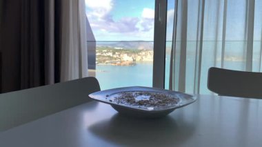 Açık bir pencereden deniz, kıyı şeridi ve Yunanistan 'ın mavi kepenkleri görünüyor.