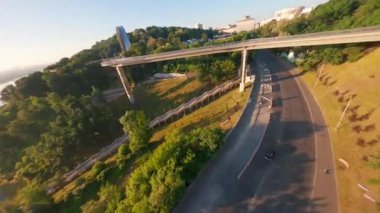 KIEV, Ukrayna - 19 Nisan 2021: FPV drone, Reunion Arch, Kyiv: Halkların Dostluk Kemeri ve Volodymyr Tepesi köprüsü. Kiev 'deki parkın ve yaya köprüsünün manzarası. Parktaki insanlar ve yeşil ağaçlar. 