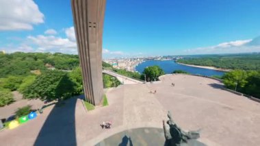 KIEV, Ukrayna - 19 Nisan 2021: FPV drone, Reunion Arch, Kyiv: Halkların Dostluk Kemeri ve Volodymyr Tepesi köprüsü. Kiev 'deki parkın ve yaya köprüsünün manzarası. Parktaki insanlar ve yeşil ağaçlar. 