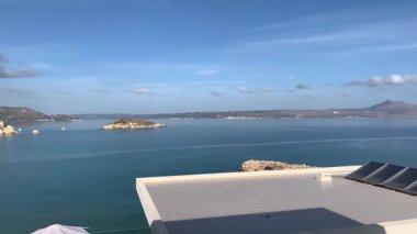 Açık bir pencereden deniz, kıyı şeridi ve Yunanistan 'ın mavi kepenkleri görünüyor.