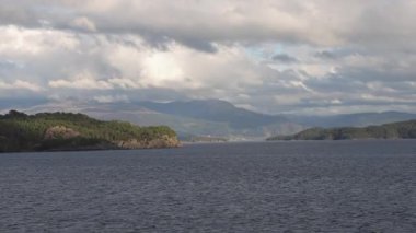 Norveç 'te gezinti. Bottan fiyordun manzarası, tekneden dağların manzarası, şelaleler, yolcu gemileri ve hassas tekneler turistleri gemiden kıyıya taşıyan mavi gökyüzü ile güzel bir günde
