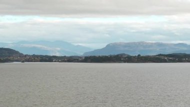 Norveç 'te gezinti. Bottan fiyordun manzarası, tekneden dağların manzarası, şelaleler, yolcu gemileri ve hassas tekneler turistleri gemiden kıyıya taşıyan mavi gökyüzü ile güzel bir günde