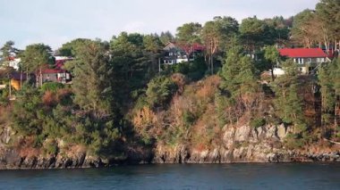 Norveç 'te gezinti. Bottan fiyordun manzarası, tekneden dağların manzarası, şelaleler, yolcu gemileri ve hassas tekneler turistleri gemiden kıyıya taşıyan mavi gökyüzü ile güzel bir günde