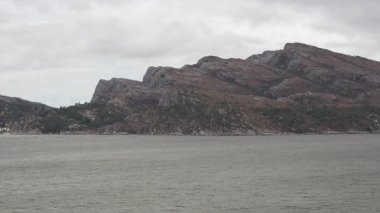 Norveç 'te gezinti. Bottan fiyordun manzarası, tekneden dağların manzarası, şelaleler, yolcu gemileri ve hassas tekneler turistleri gemiden kıyıya taşıyan mavi gökyüzü ile güzel bir günde