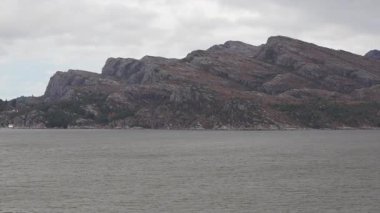 Norveç 'te gezinti. Bottan fiyordun manzarası, tekneden dağların manzarası, şelaleler, yolcu gemileri ve hassas tekneler turistleri gemiden kıyıya taşıyan mavi gökyüzü ile güzel bir günde