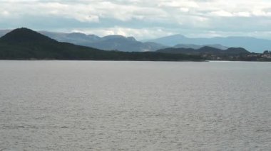 Norveç 'te gezinti. Bottan fiyordun manzarası, tekneden dağların manzarası, şelaleler, yolcu gemileri ve hassas tekneler turistleri gemiden kıyıya taşıyan mavi gökyüzü ile güzel bir günde