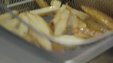 Ticari bir mutfakta çalışan profesyonel bir aşçı yemek pişirme tavaları ve diğer mutfak malzemelerinden yükselen buharlı bir yemek hazırlıyor.