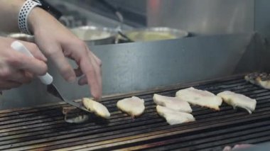 Ticari bir mutfakta çalışan profesyonel bir aşçı yemek pişirme tavaları ve diğer mutfak malzemelerinden yükselen buharlı bir yemek hazırlıyor.