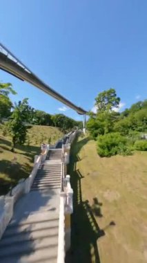 KIEV, Ukrayna - 19 Nisan 2021: FPV drone, Reunion Arch, Kyiv: Halkların Dostluk Kemeri ve Volodymyr Tepesi köprüsü. Kiev 'deki parkın ve yaya köprüsünün manzarası. Parktaki insanlar ve yeşil ağaçlar. 