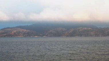 Norveç 'te gezinti. Bottan fiyordun manzarası, tekneden dağların manzarası, şelaleler, yolcu gemileri ve hassas tekneler turistleri gemiden kıyıya taşıyan mavi gökyüzü ile güzel bir günde