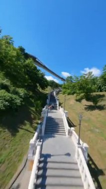 KIEV, Ukrayna - 19 Nisan 2021: FPV drone, Reunion Arch, Kyiv: Halkların Dostluk Kemeri ve Volodymyr Tepesi köprüsü. Kiev 'deki parkın ve yaya köprüsünün manzarası. Parktaki insanlar ve yeşil ağaçlar. 