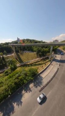 KIEV, Ukrayna - 19 Nisan 2021: FPV drone, Reunion Arch, Kyiv: Halkların Dostluk Kemeri ve Volodymyr Tepesi köprüsü. Kiev 'deki parkın ve yaya köprüsünün manzarası. Parktaki insanlar ve yeşil ağaçlar. 