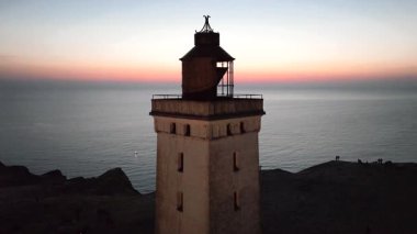 Tepenin tepesinde ünlü deniz feneri olan dev kum tepelerinin hava manzarası. Rubjerg Knude Deniz Feneri, Kuzey Deniz Rubjerg, Danimarka Lokken yakınlarındaki Rubjerg Knude Fyr deniz fenerinde gün batımı. 