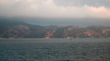 Norveç 'te gezinti. Bottan fiyordun manzarası, tekneden dağların manzarası, şelaleler, yolcu gemileri ve hassas tekneler turistleri gemiden kıyıya taşıyan mavi gökyüzü ile güzel bir günde