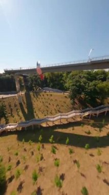 KIEV, Ukrayna - 19 Nisan 2021: FPV drone, Reunion Arch, Kyiv: Halkların Dostluk Kemeri ve Volodymyr Tepesi köprüsü. Kiev 'deki parkın ve yaya köprüsünün manzarası. Parktaki insanlar ve yeşil ağaçlar. 