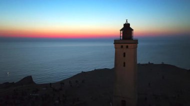 Tepenin tepesinde ünlü deniz feneri olan dev kum tepelerinin hava manzarası. Rubjerg Knude Deniz Feneri, Kuzey Deniz Rubjerg, Danimarka Lokken yakınlarındaki Rubjerg Knude Fyr deniz fenerinde gün batımı. 