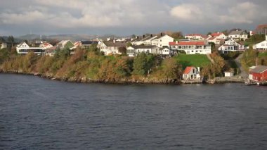 Norveç 'te gezinti. Bottan fiyordun manzarası, tekneden dağların manzarası, şelaleler, yolcu gemileri ve hassas tekneler turistleri gemiden kıyıya taşıyan mavi gökyüzü ile güzel bir günde