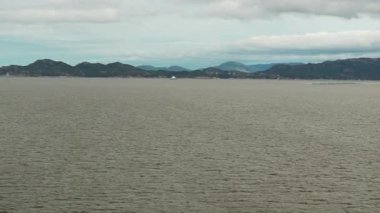 Norveç 'te gezinti. Bottan fiyordun manzarası, tekneden dağların manzarası, şelaleler, yolcu gemileri ve hassas tekneler turistleri gemiden kıyıya taşıyan mavi gökyüzü ile güzel bir günde