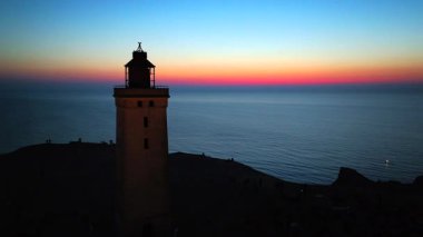 Tepenin tepesinde ünlü deniz feneri olan dev kum tepelerinin hava manzarası. Rubjerg Knude Deniz Feneri, Kuzey Deniz Rubjerg, Danimarka Lokken yakınlarındaki Rubjerg Knude Fyr deniz fenerinde gün batımı. 