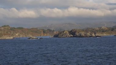 Norveç 'te gezinti. Bottan fiyordun manzarası, tekneden dağların manzarası, şelaleler, yolcu gemileri ve hassas tekneler turistleri gemiden kıyıya taşıyan mavi gökyüzü ile güzel bir günde