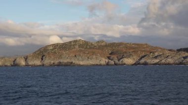 Norveç 'te gezinti. Bottan fiyordun manzarası, tekneden dağların manzarası, şelaleler, yolcu gemileri ve hassas tekneler turistleri gemiden kıyıya taşıyan mavi gökyüzü ile güzel bir günde