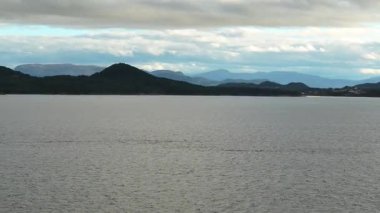 Norveç 'te gezinti. Bottan fiyordun manzarası, tekneden dağların manzarası, şelaleler, yolcu gemileri ve hassas tekneler turistleri gemiden kıyıya taşıyan mavi gökyüzü ile güzel bir günde