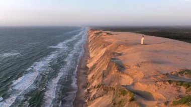 Tepenin tepesinde ünlü deniz feneri olan dev kum tepelerinin hava manzarası. Rubjerg Knude Deniz Feneri, Kuzey Deniz Rubjerg, Danimarka Lokken yakınlarındaki Rubjerg Knude Fyr deniz fenerinde gün batımı. 